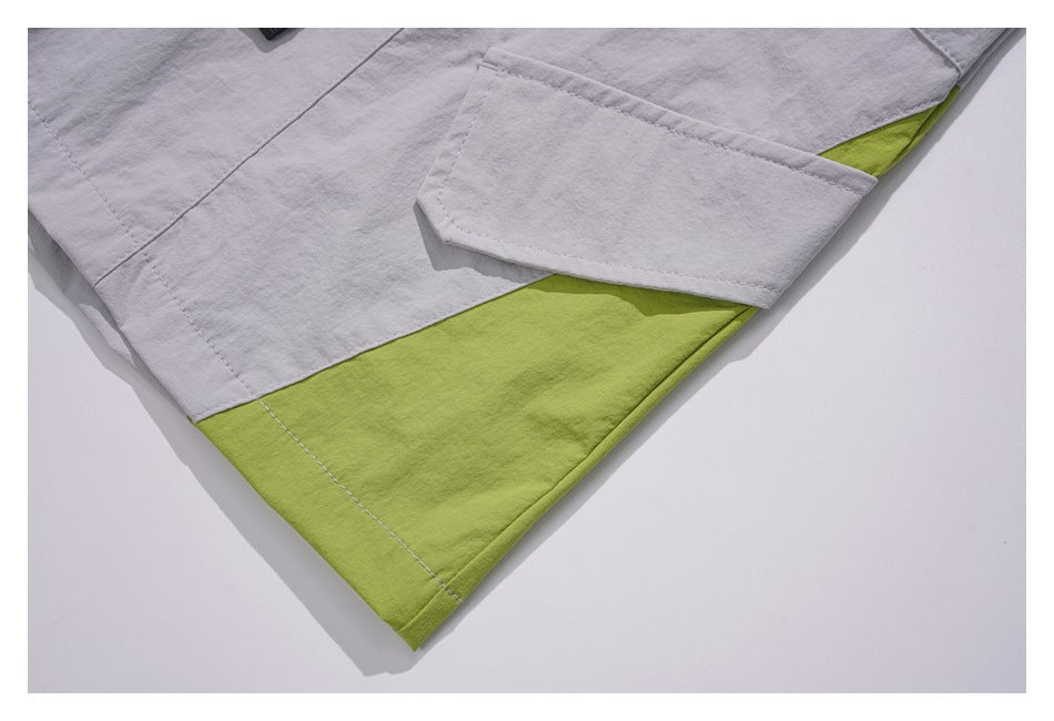Close-up of light gray bottoms with a flap pocket and a lime green contrast panel near the hem.
