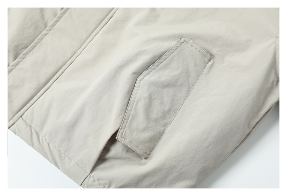 Close-up of a large patch pocket and lower seam on a cream coat laid flat.