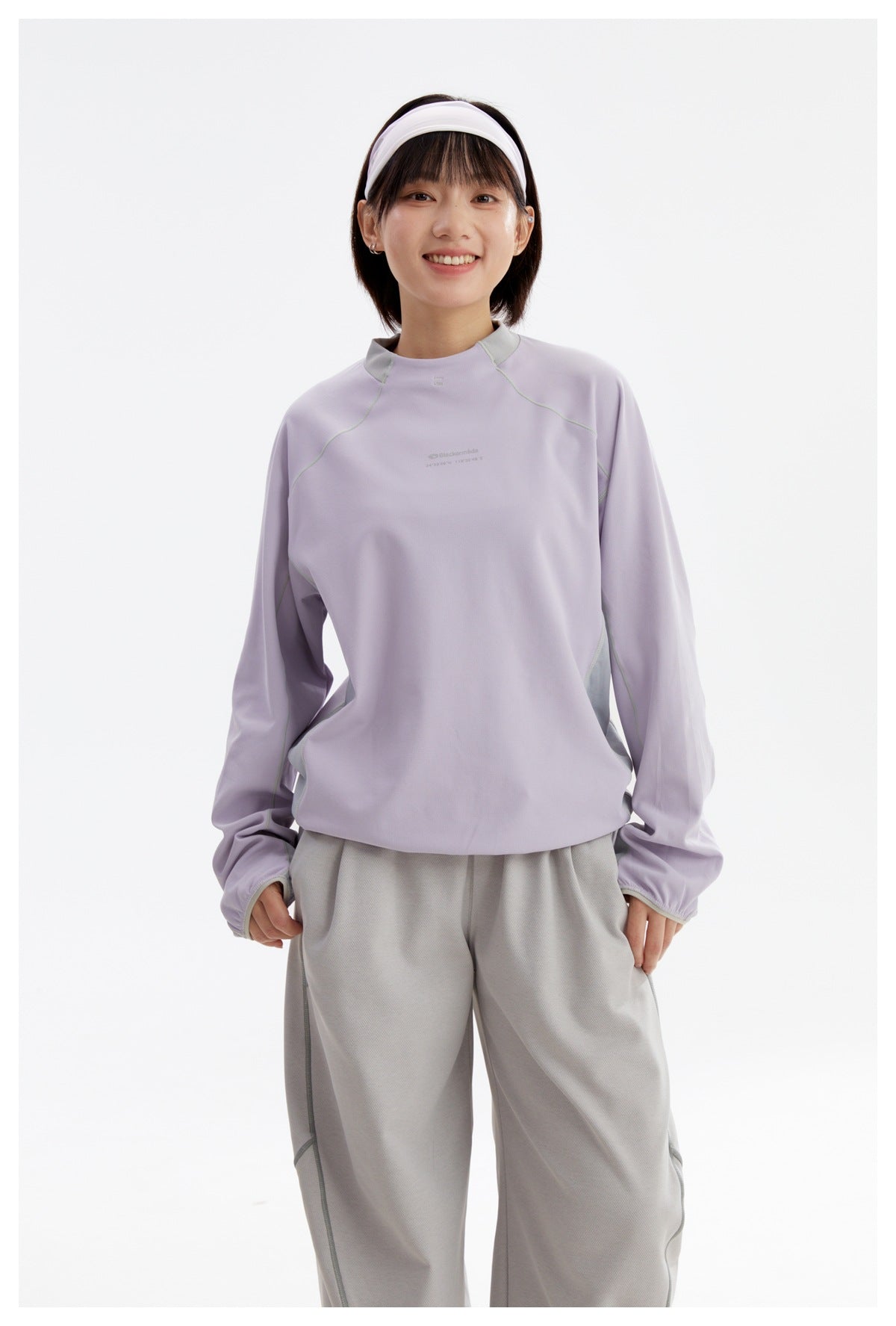 Model wearing a lavender long-sleeve top with a pale gray stand collar and side panels, paired with loose gray pants.