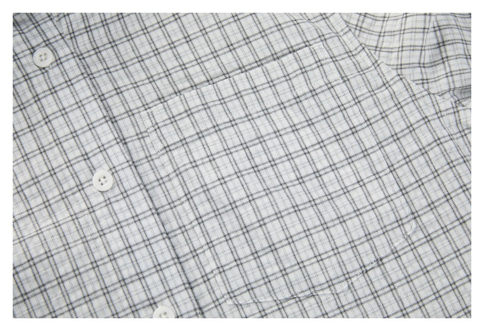 Close-up of white buttons and plaid fabric on the front of a white and gray checked shirt.