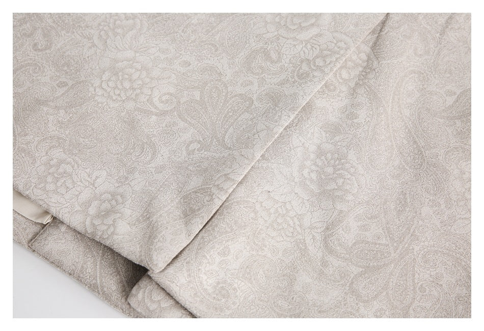Overlapping panels of light taupe fabric with an ornate paisley and floral pattern.