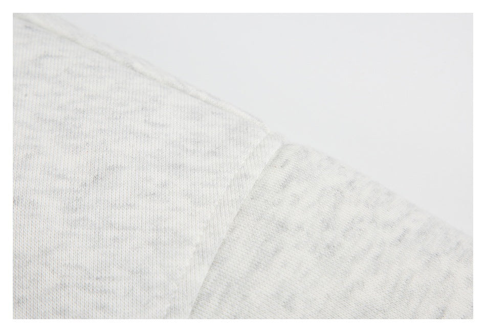 Close-up of a seam and the lightly mottled knit surface of the light gray hoodie.