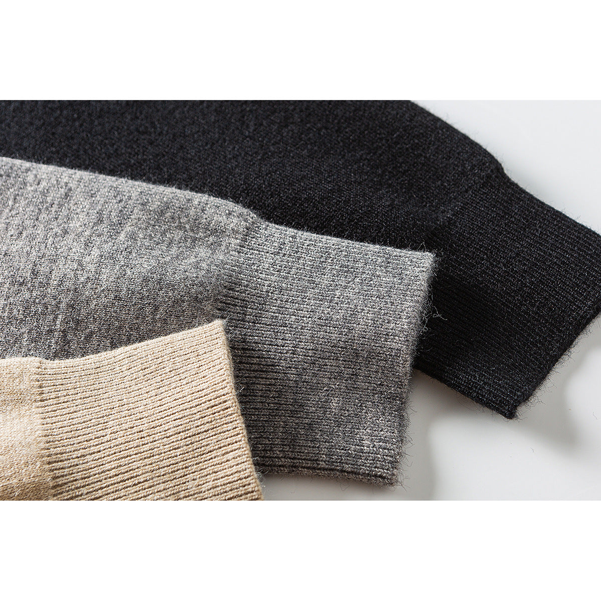 Close-up of ribbed cardigan cuffs in black, heather gray, and beige.