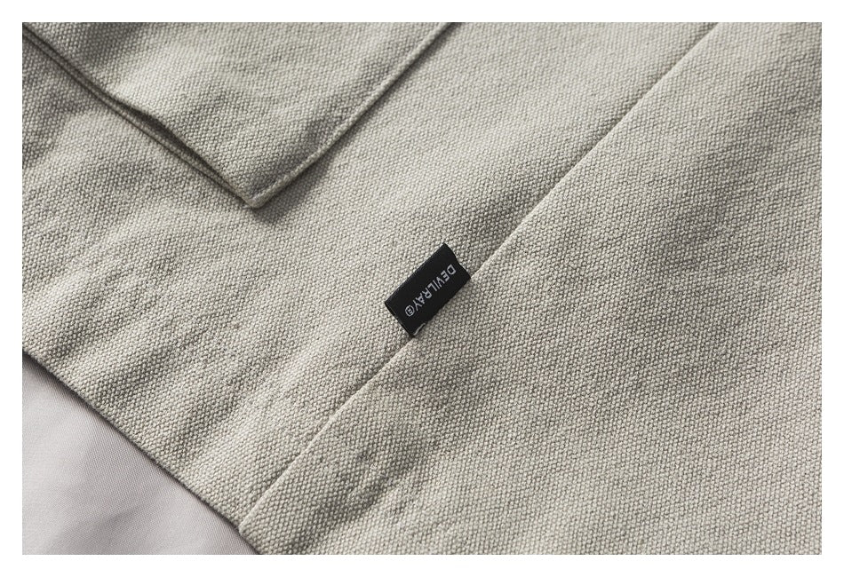 Close-up of beige jacket fabric and a small black sewn-in label with light lettering.