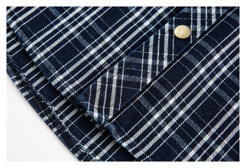 Close-up of navy-and-white plaid shirt fabric with a stitched seam and brass-colored button.
