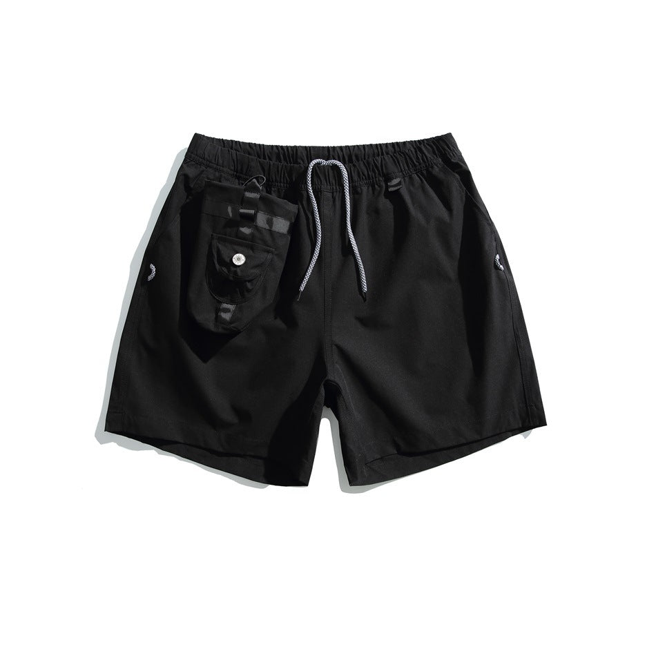 Black drawstring shorts with an elastic waist, side pockets, and an attached flap pouch.