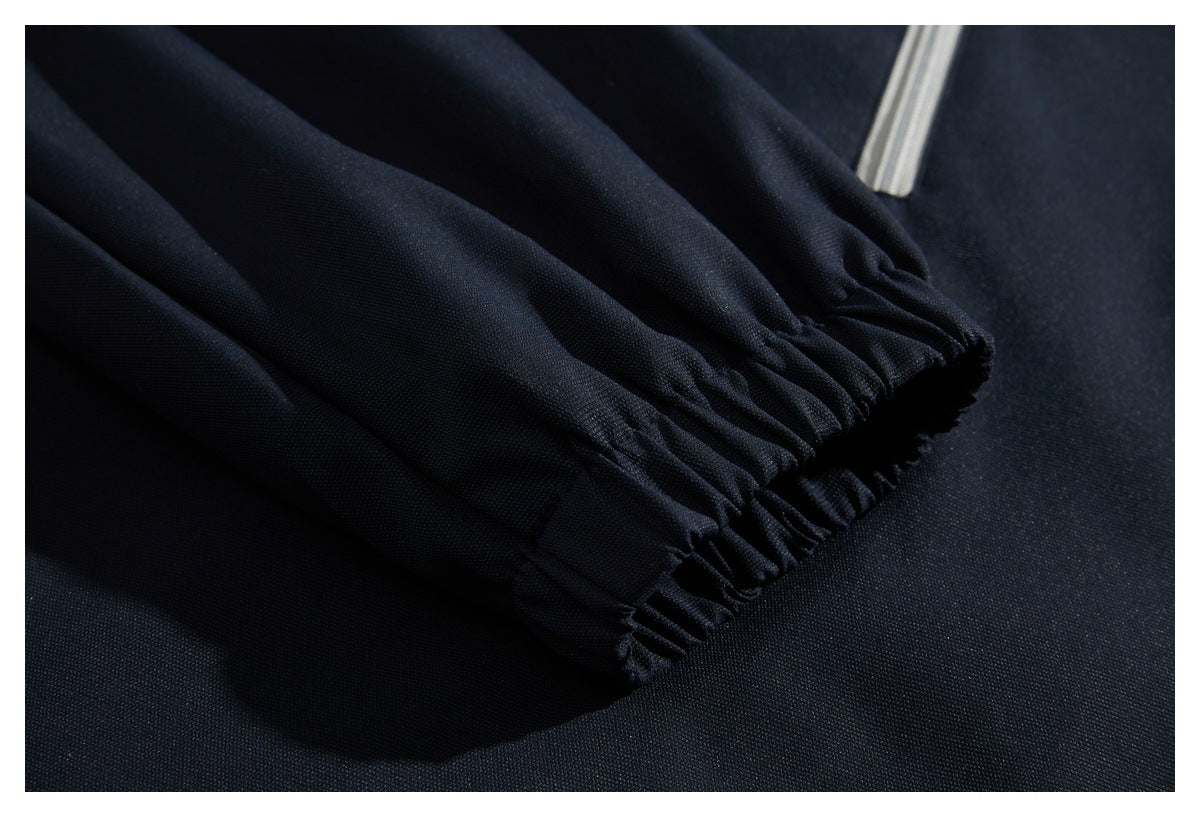 Close-up of a gathered elastic cuff on a dark navy sleeve beside a light-colored zipper.