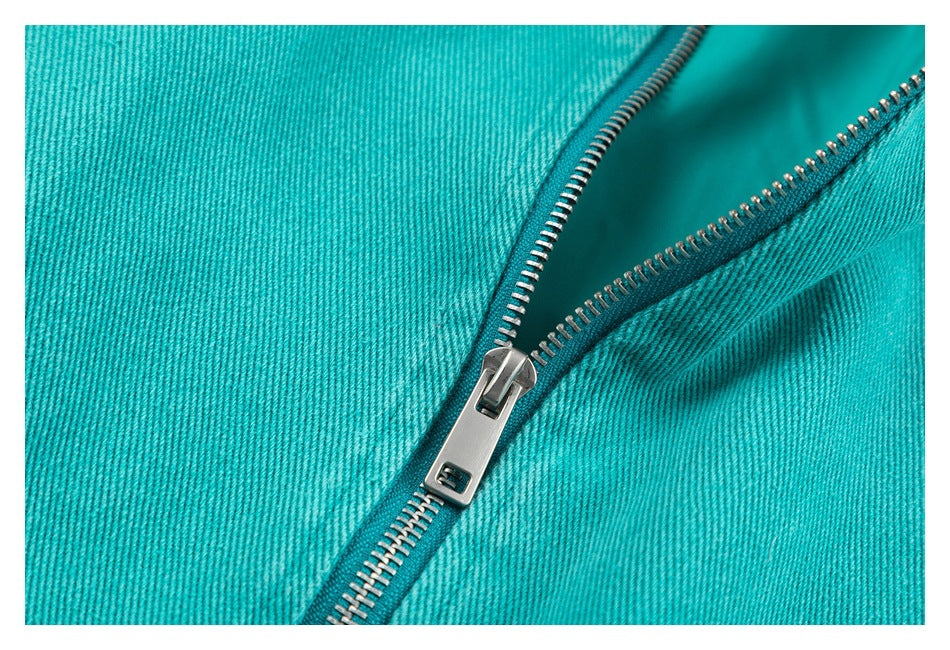 Close-up of a silver zipper and turquoise fabric on the jacket.