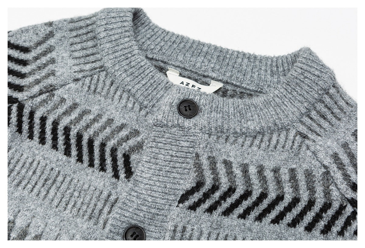 Close-up of a gray knit cardigan's ribbed collar, black buttons, and dark geometric pattern.