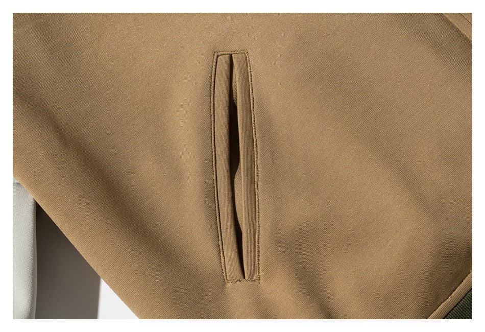 Close-up of a narrow welt pocket on the tan jacket, with part of a cream sleeve visible.