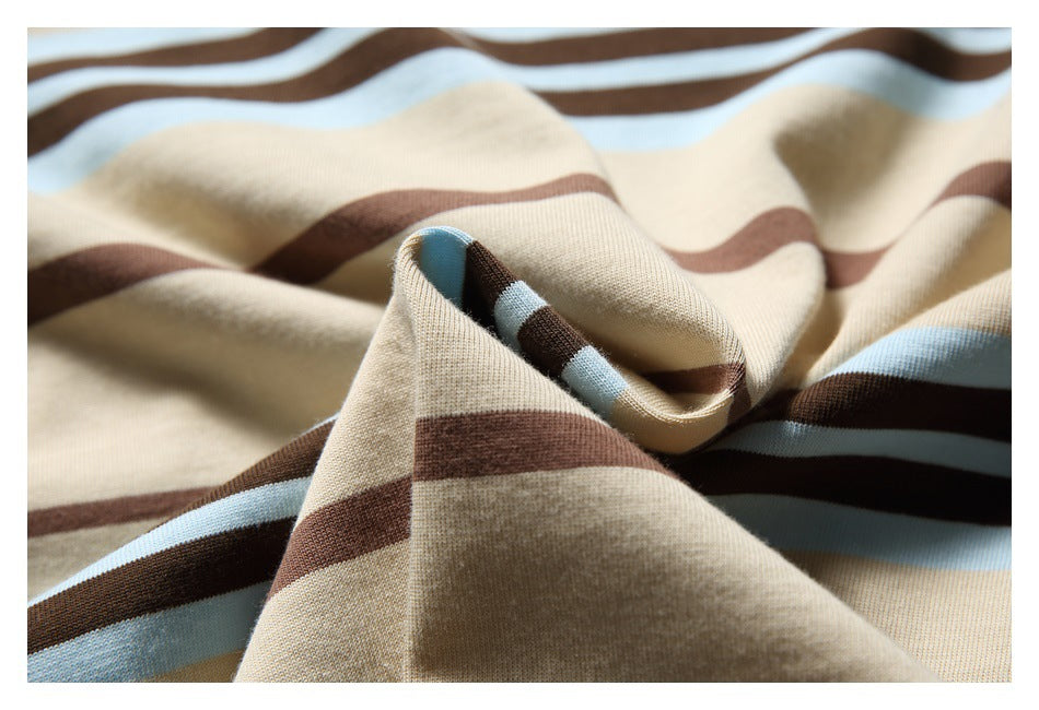 Close-up of beige fabric with wavy brown and pale blue stripes, folded into soft ridges.