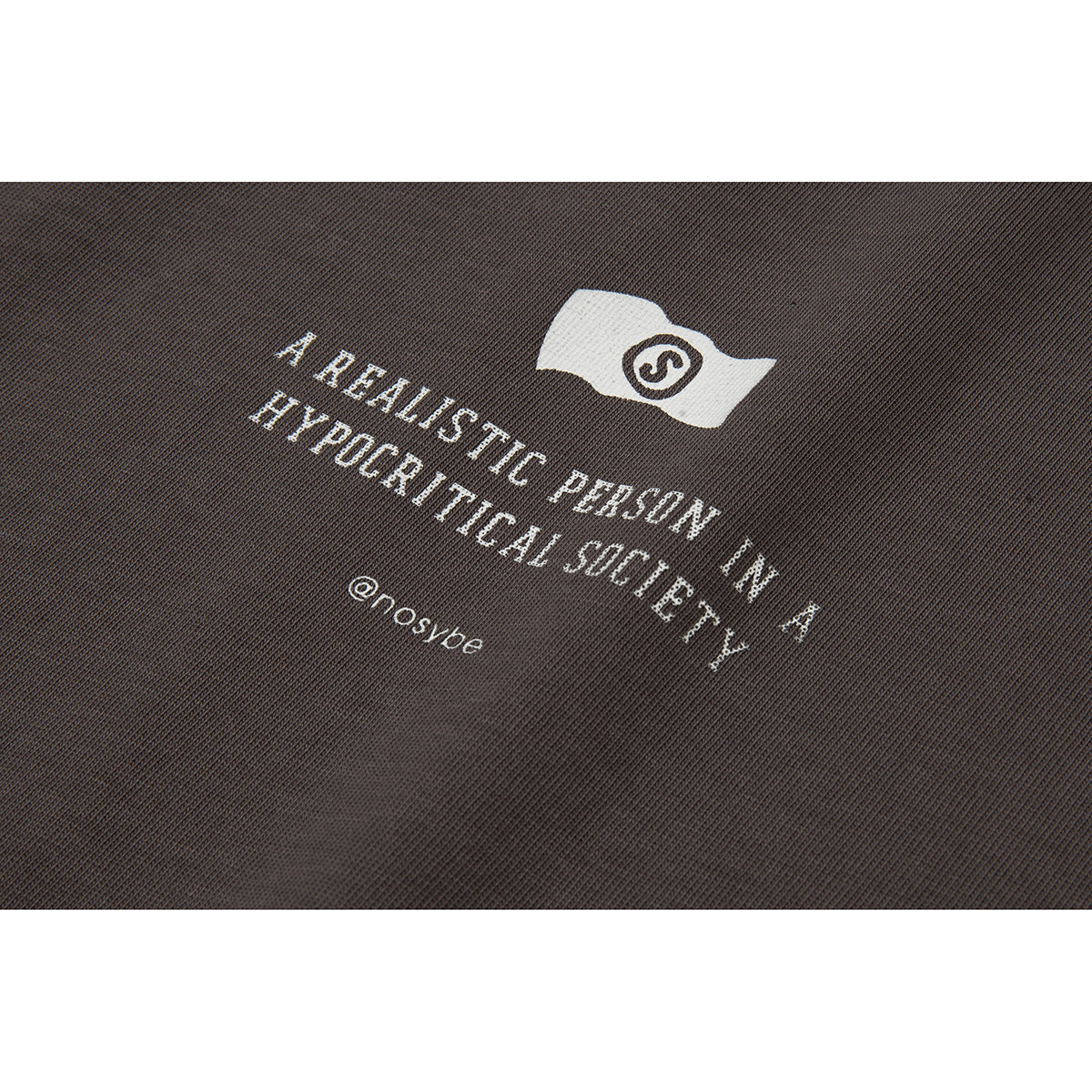 Close-up of a dark brown shirt with a white emblem and slogan printed on the fabric.