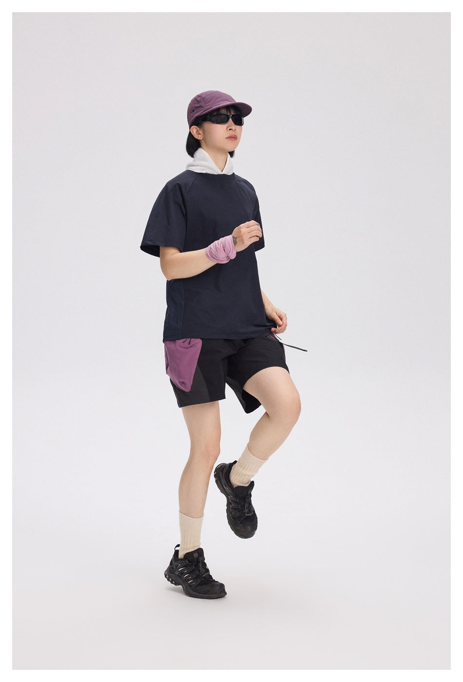 Model wearing a loose dark navy short-sleeve T-shirt with black shorts featuring purple panels.
