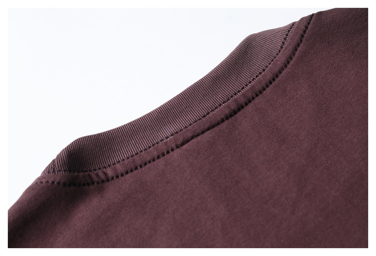 Close-up of a dark burgundy garment's ribbed crew neckline and stitched seam against a white background.