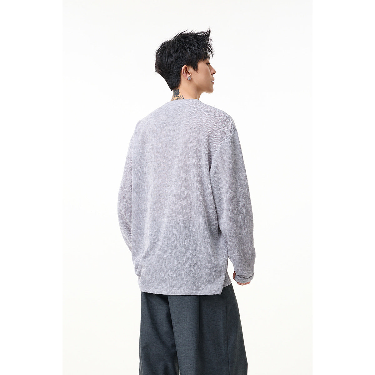 Back view of a model wearing a light gray textured long-sleeve top with dark trousers.
