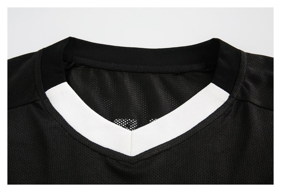 Close-up of a black mesh jersey's neckline with a white V-shaped insert and black ribbed collar.