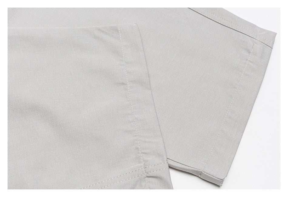 Close-up of light gray garment panels with stitched seams and a folded hem.