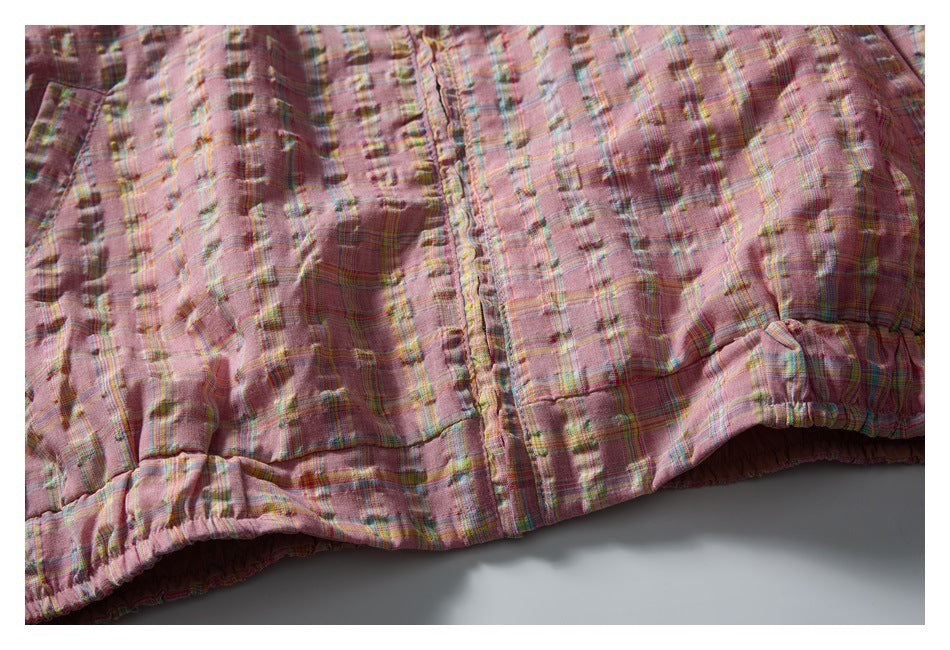 Close-up of the jacket’s pink multicolor plaid fabric and gathered elastic hem.