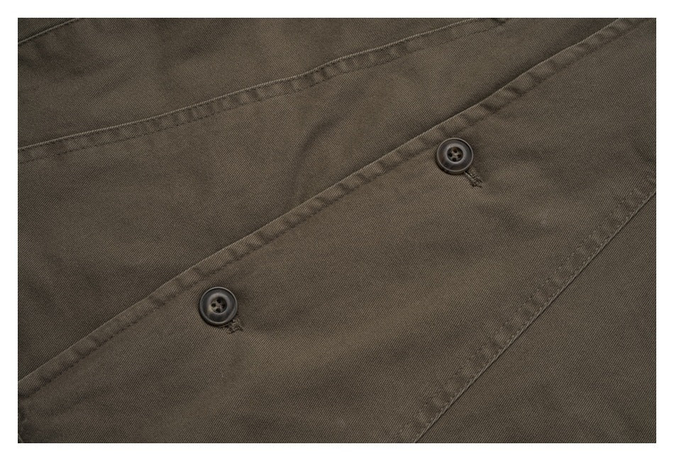 Close-up of two dark buttons and stitched seams on the olive-brown jacket.