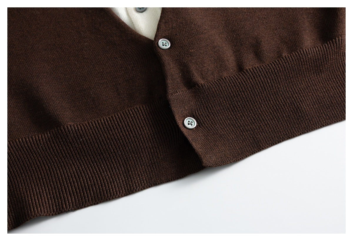 Close-up of a dark brown cardigan's button placket and ribbed hem, with a cream layer visible at the neckline.