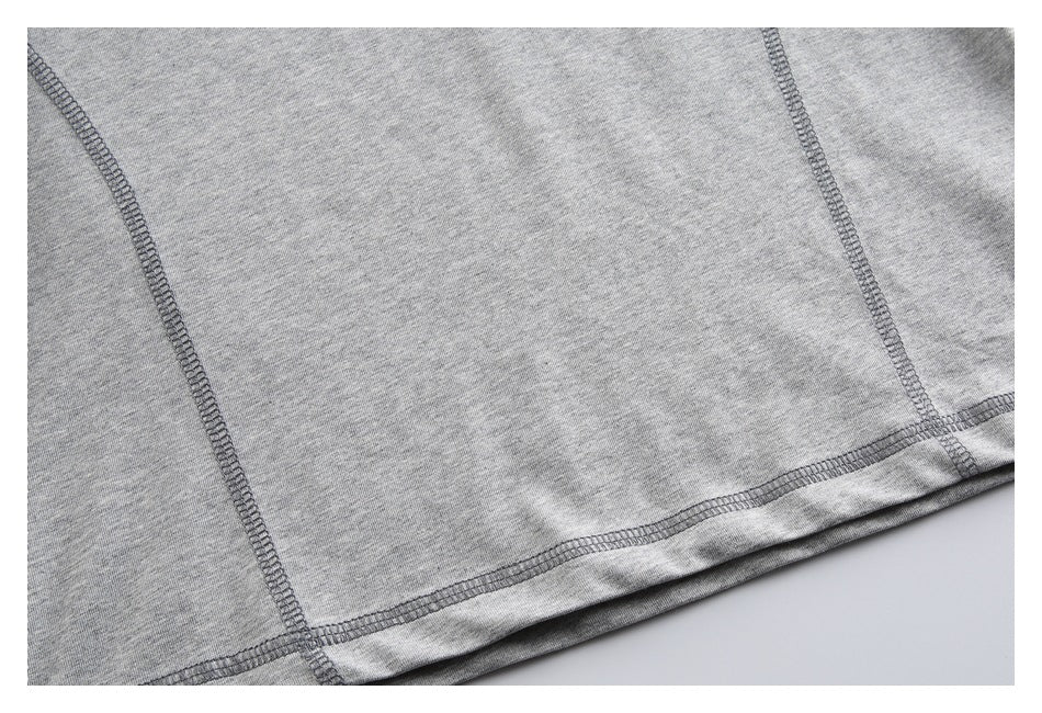 Close-up of a gray garment hem with visible overlock stitching and panel seams.