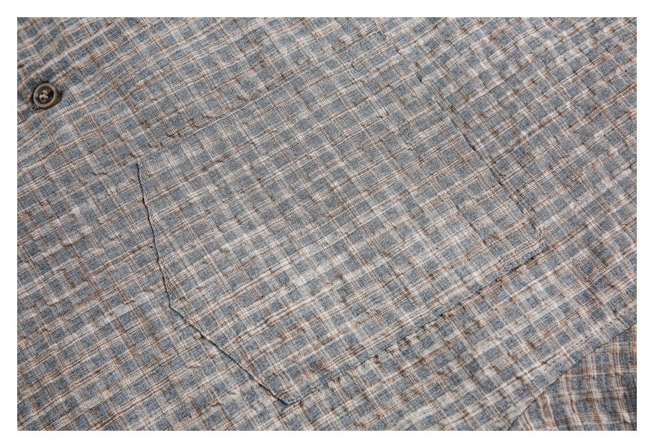 Close-up of blue-gray plaid shirt fabric with a button and chest pocket seam.