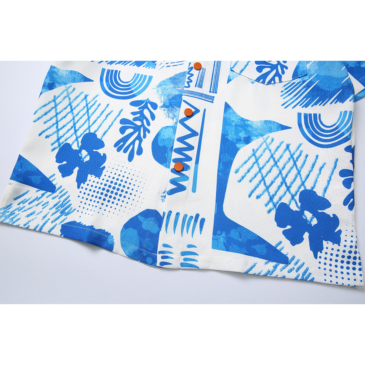 Close-up of the shirt's blue-and-white abstract print, orange buttons and lower hem.