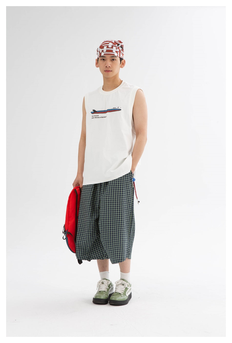 Model wearing navy and green plaid wide-leg shorts with white sleeveless top and green sneakers