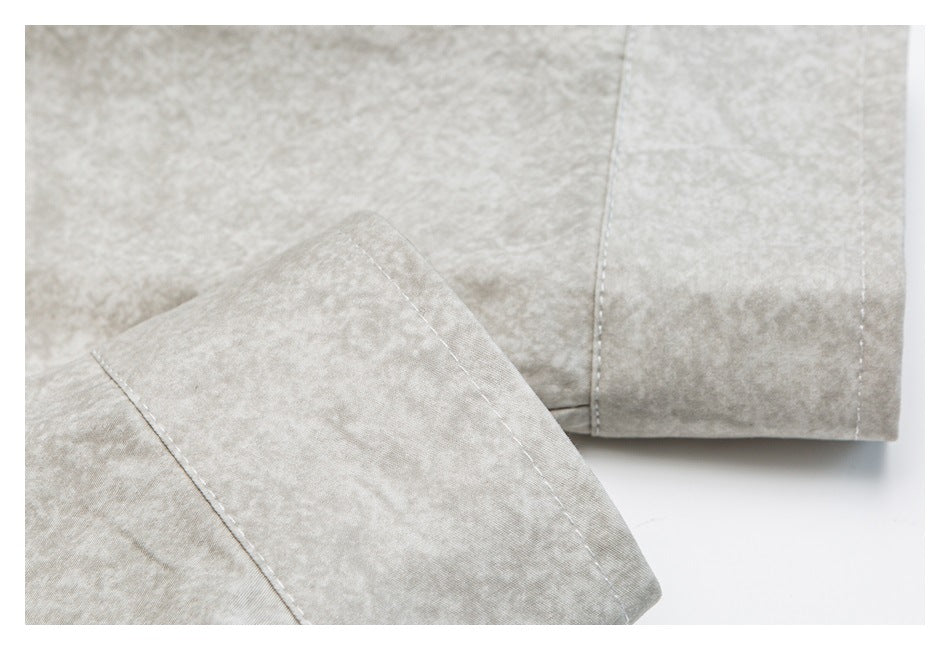 Close-up of a light beige mottled garment with stitched seams and a folded edge.