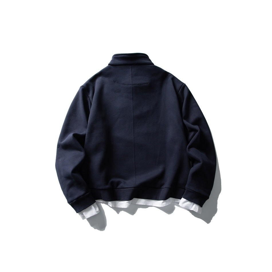 Back view of navy sweatshirt with center seam, ribbed hem and cuffs, and white shirt hem and cuffs underneath