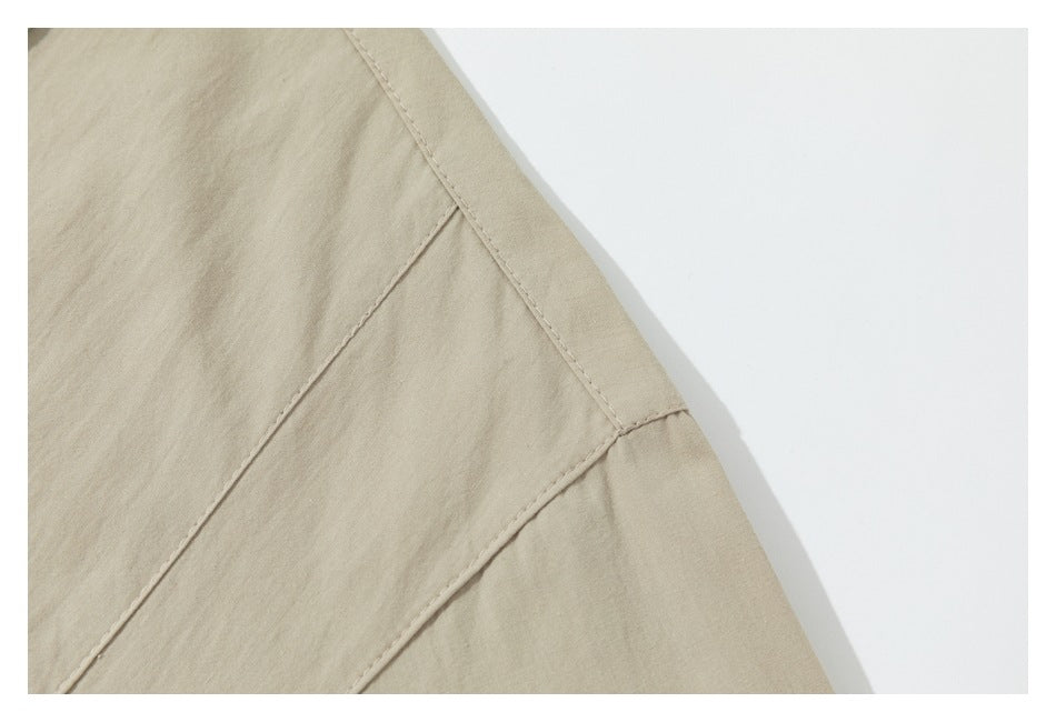 Close-up of a beige garment panel with intersecting stitched seams.