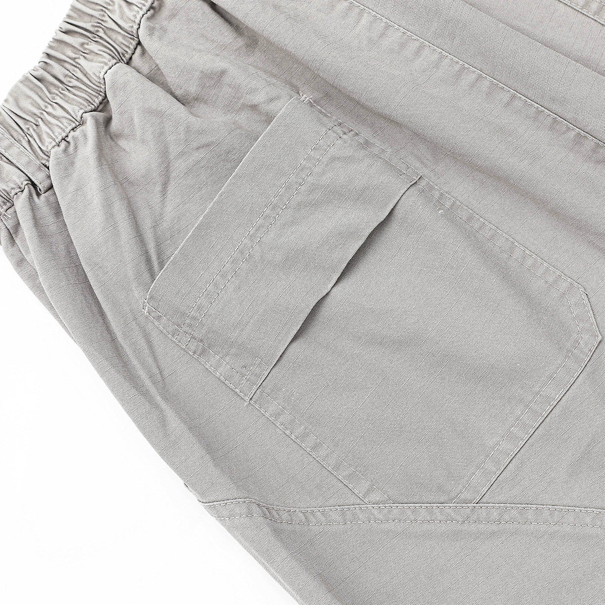 Close-up of light gray trousers showing an elasticated waistband and a large back patch pocket.