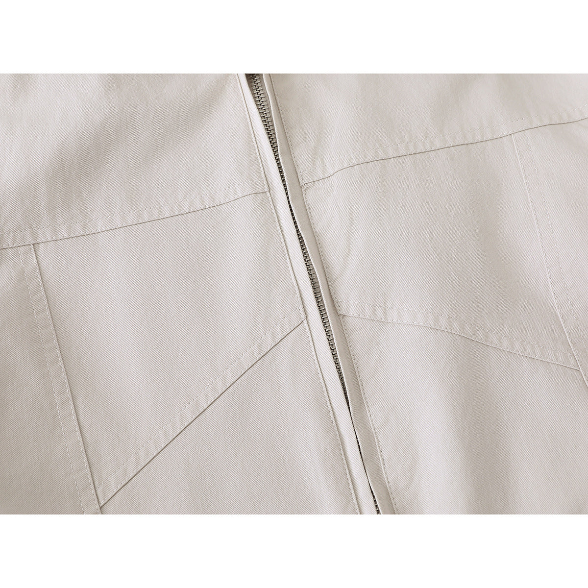 Close-up of an ivory jacket’s front zipper, stitched panels, and angled pocket openings.