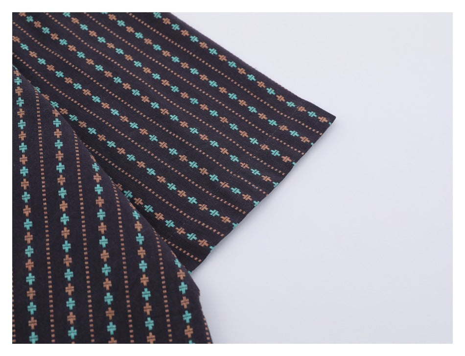 Close-up of the short sleeve and hem on a dark shirt with turquoise and rust motifs.