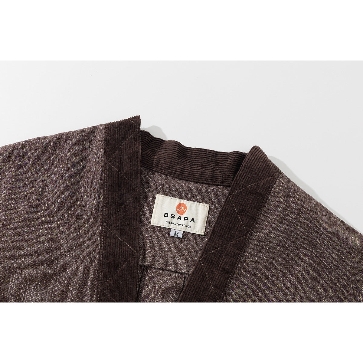 Close-up of a brown jacket collar and inner neck label, with dark ribbed trim and a size M tag.