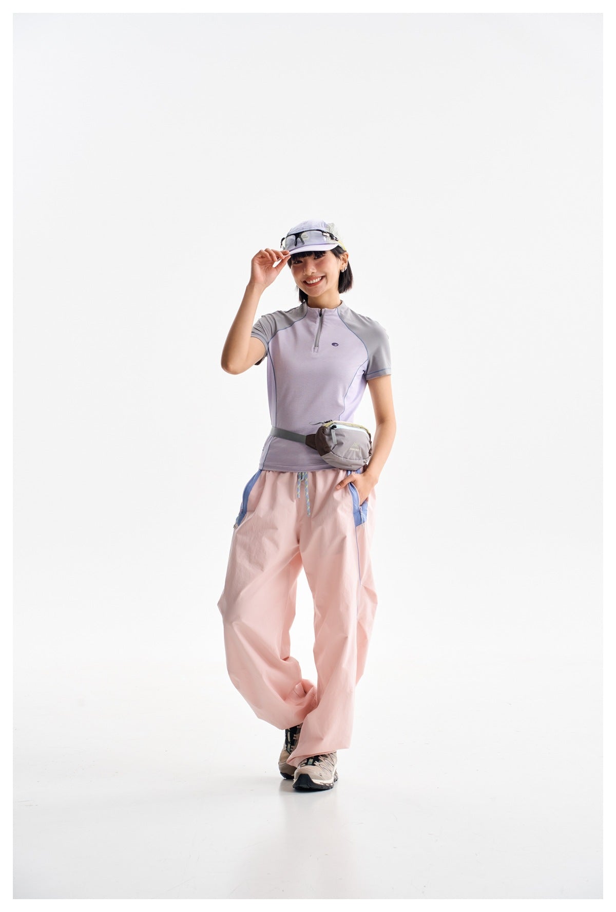 Model wearing a lavender and gray short-sleeve zip-neck top with loose pale pink pants.
