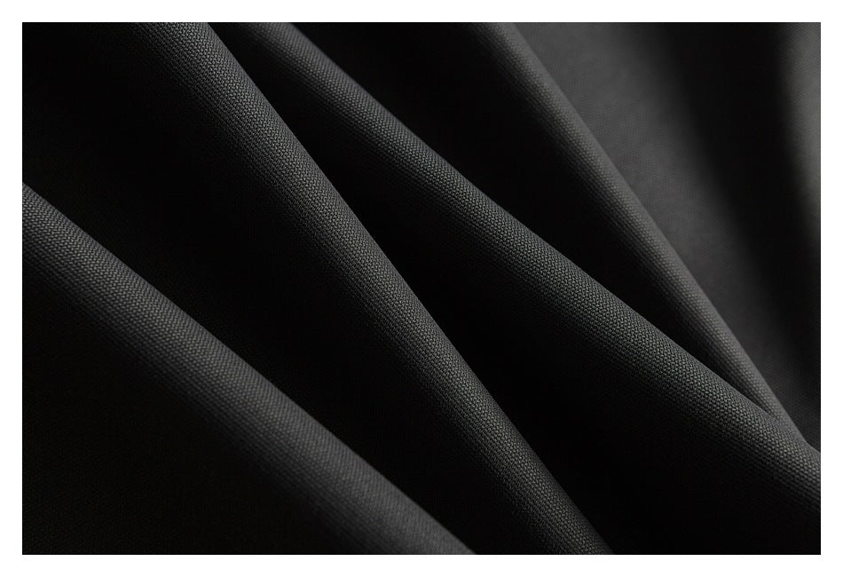 Close-up of black fabric draped in soft folds, showing its fine textured surface.