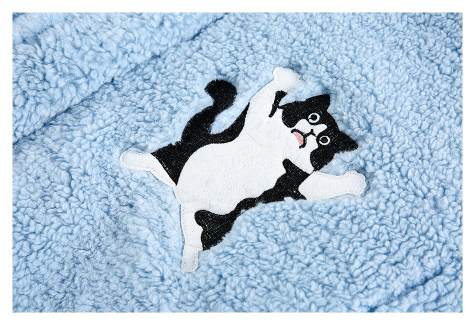 Close-up of a black-and-white cat applique on pale blue plush fabric.