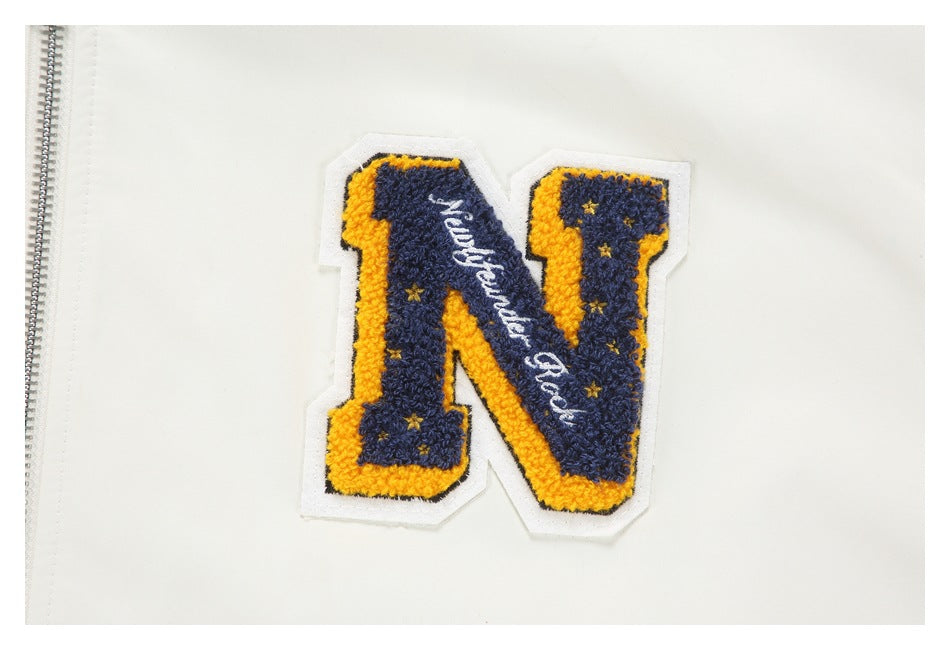 Close-up of a fuzzy navy-and-yellow embroidered N patch with white script on a white garment.
