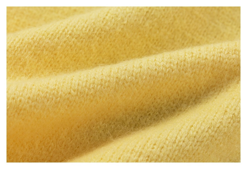 Macro view of pale yellow knit fabric folded to show its textured stitches.