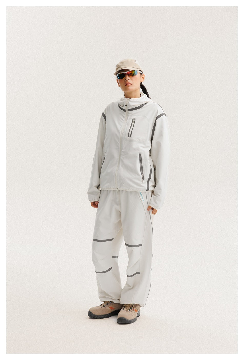 Model standing in a white hooded jacket and matching loose pants with gray trim.