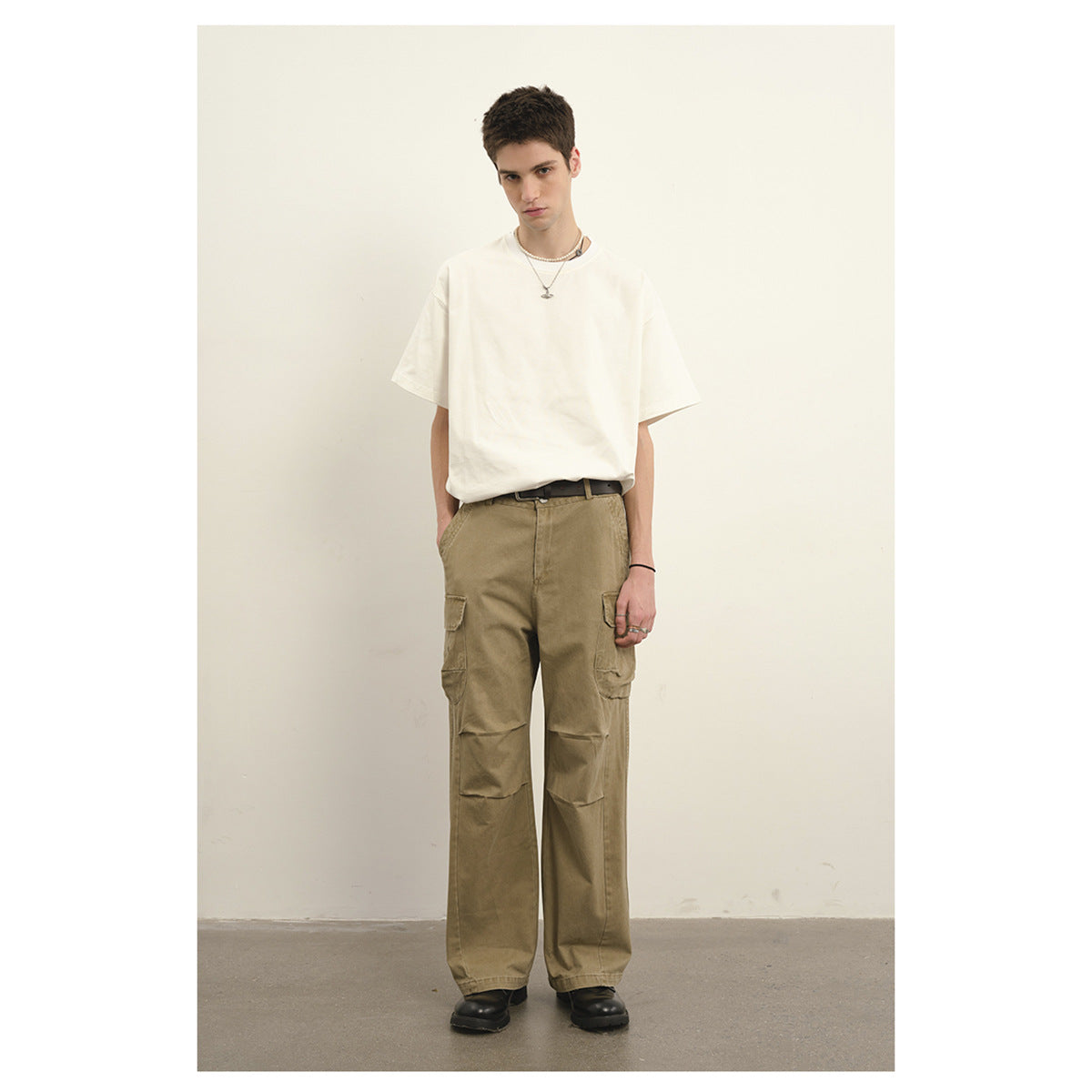 Model wearing a plain white T-shirt and loose khaki cargo pants with knee panels and flap pockets.