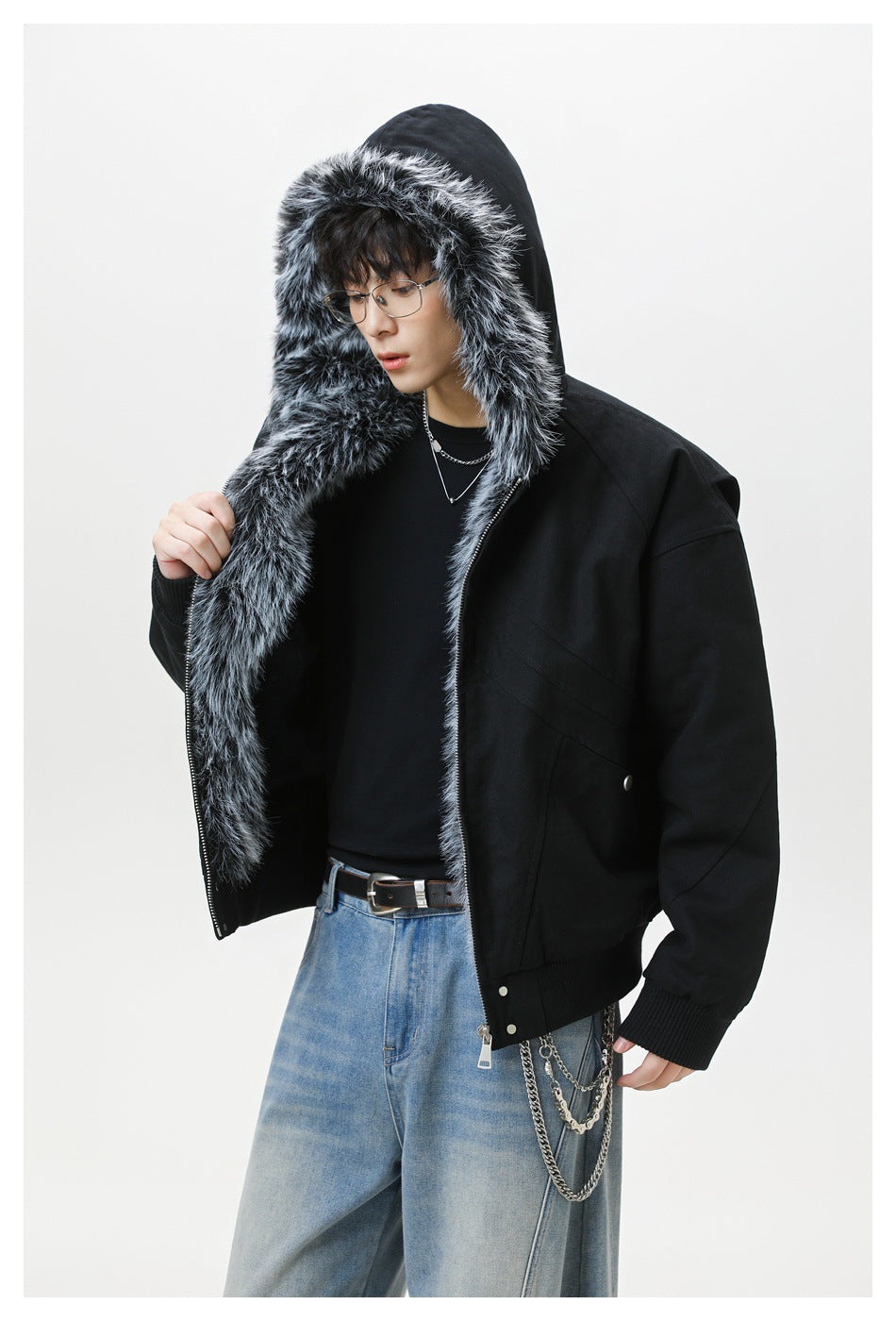 Model wearing a black hooded jacket with thick gray faux-fur trim framing the hood and zipper.