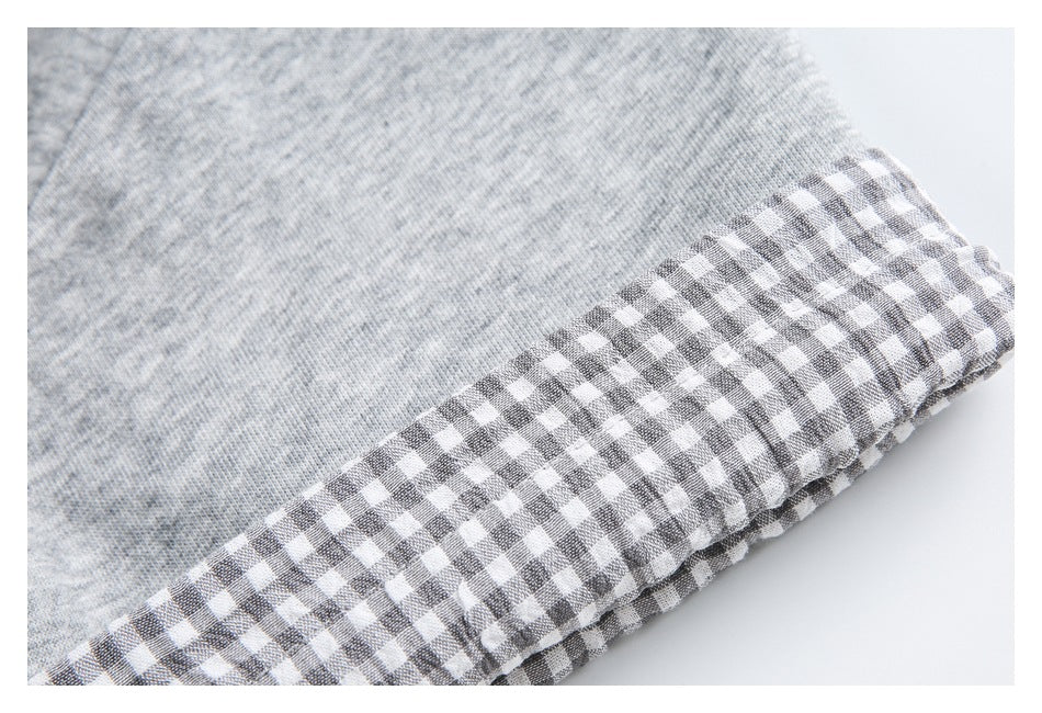 Close-up of light gray marled knit fabric finished with a gray-and-white gingham edge.
