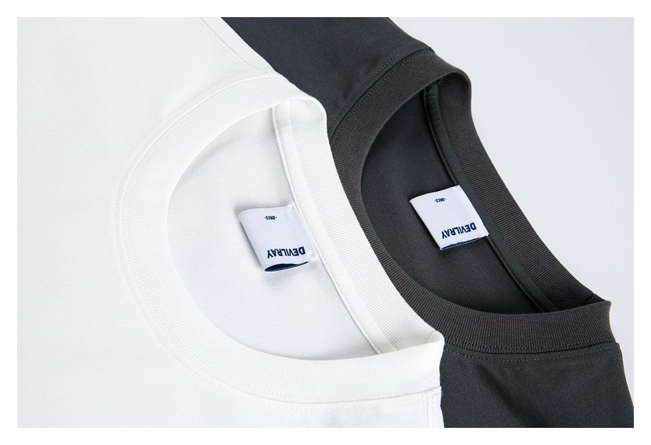 Close-up of the ribbed necklines and sewn-in labels on white and charcoal T-shirts.