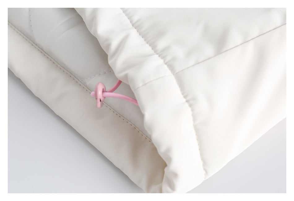 Close-up of white padded garment fabric with a pink elastic drawcord and stitched seam.