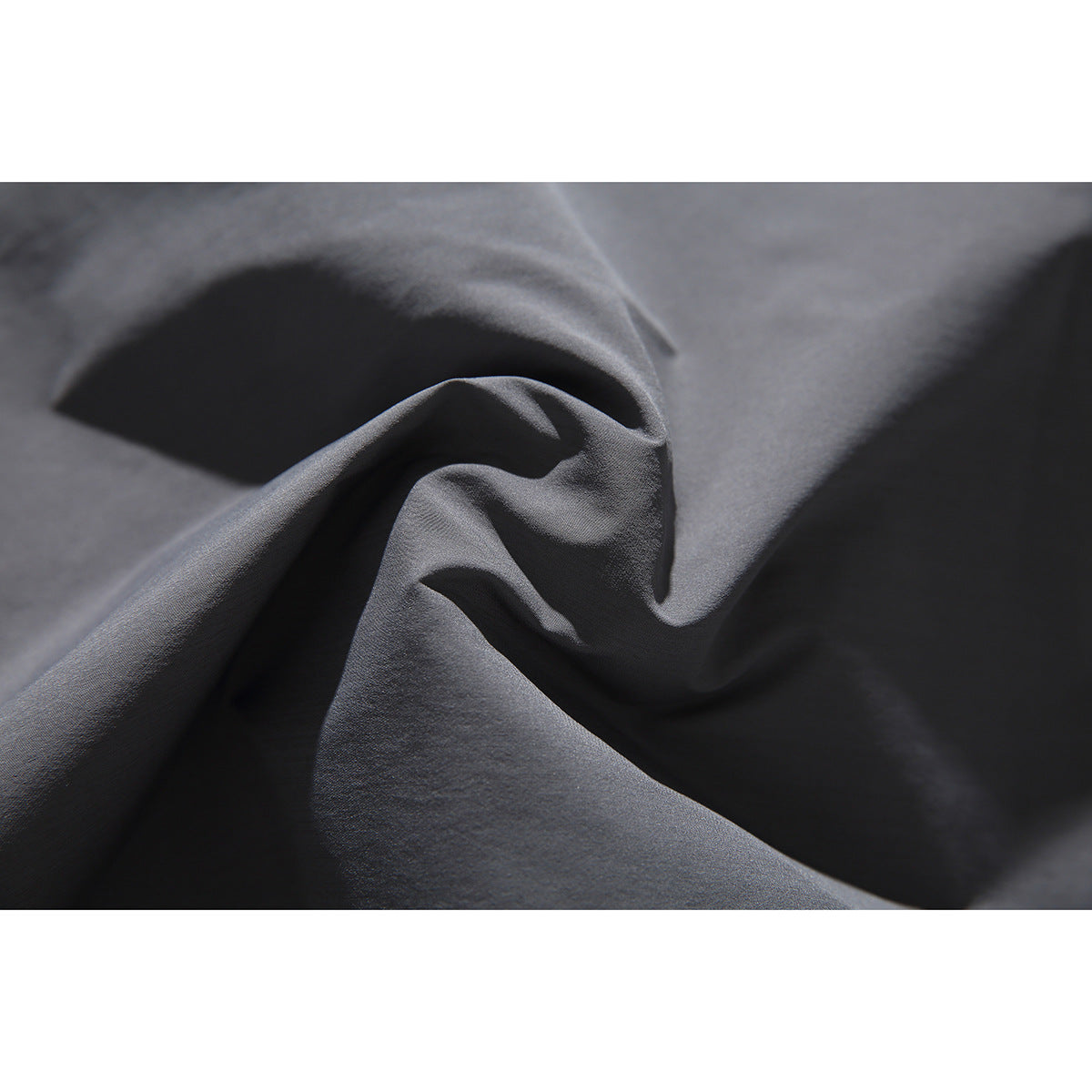 Macro view of gray fabric gathered into folds, showing its surface texture.