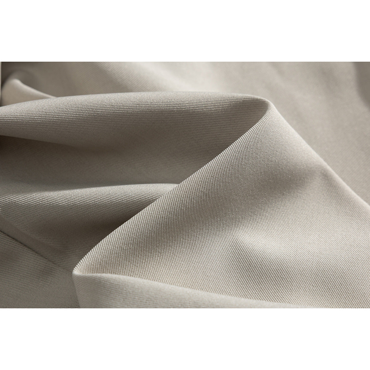 Close-up of light beige fabric folded to show its fine diagonal surface texture.