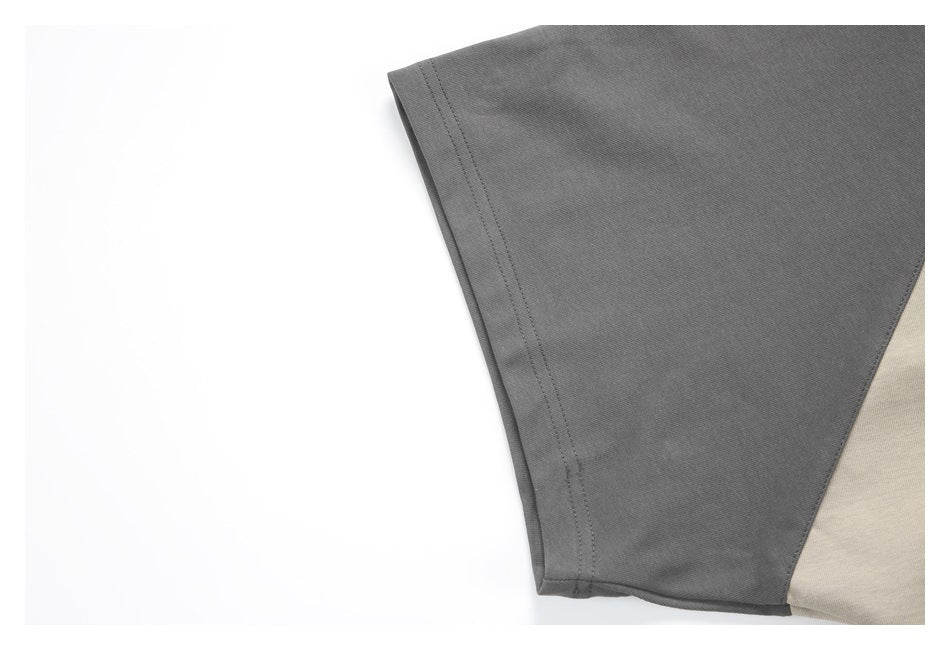 Close-up of a charcoal gray sleeve hem beside a light beige garment panel.