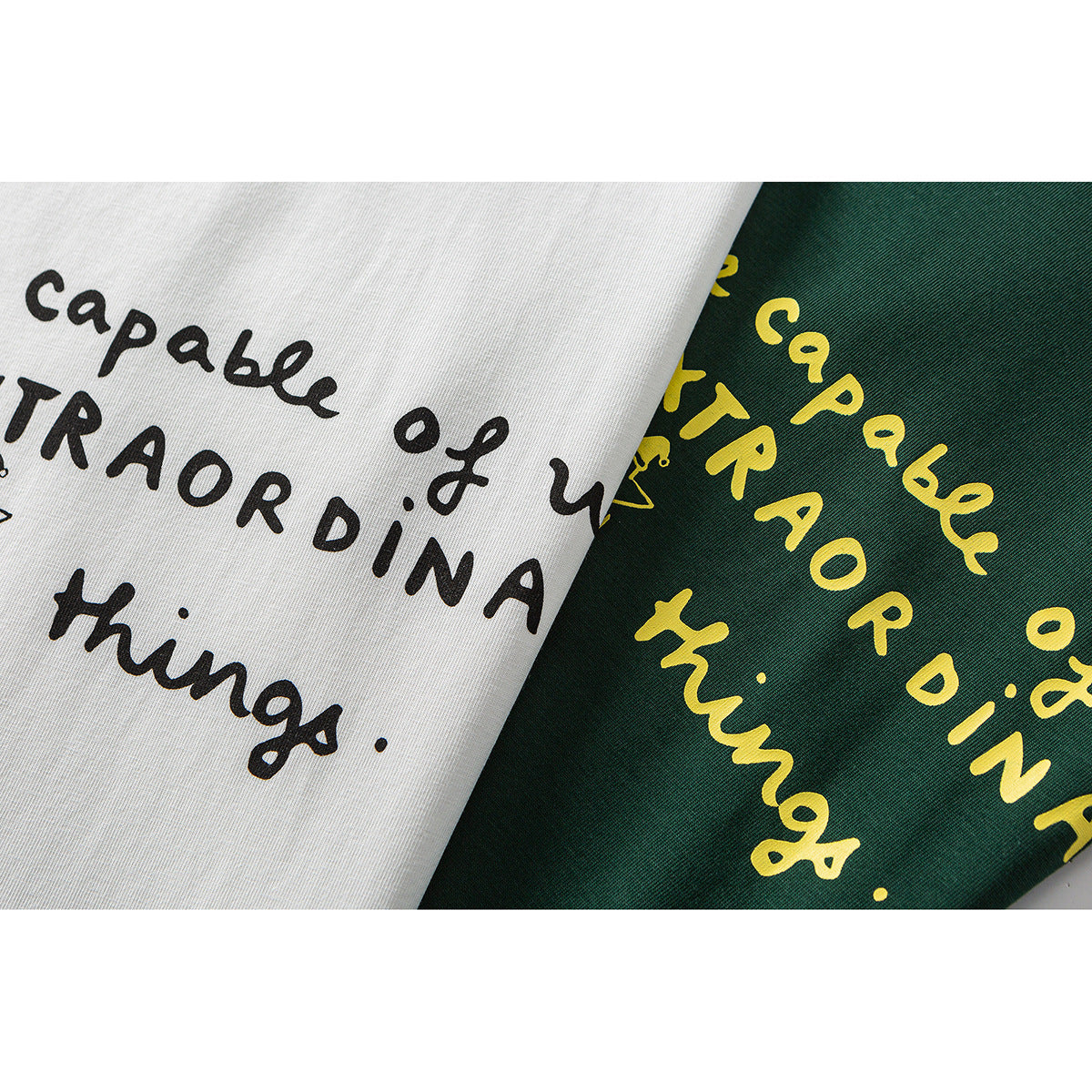 Close-up of white and dark green T-shirt fabric with contrasting handwritten English slogan prints.